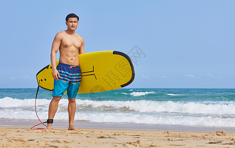 男青年抱着冲浪板奔向大海图片