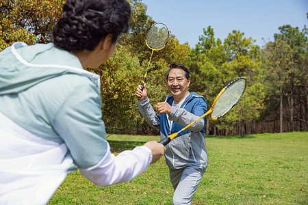 中老年运动老年夫妇在公园打羽毛球背景