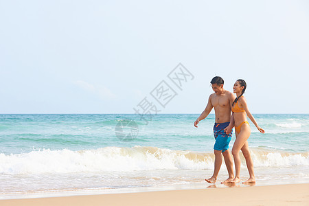 海岛旅游的男孩年轻情侣海边牵手散步背景