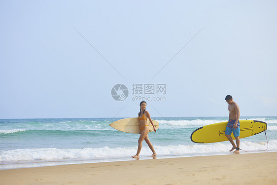 青年男女拿着冲浪板海边行走图片