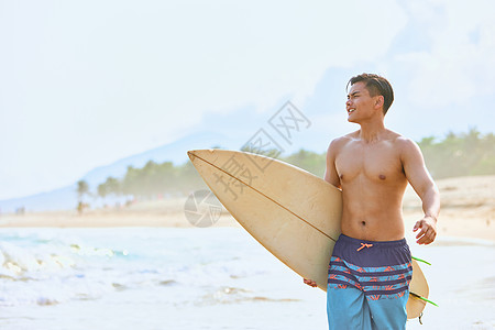 年轻男士拿着冲浪板海边行走图片