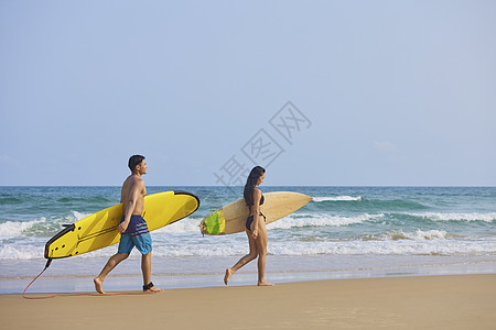 情侣性感写真年轻男女拿着冲浪板海边行走背影背景