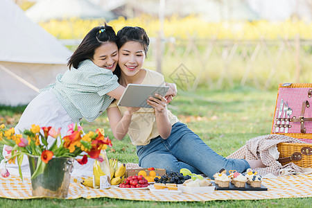 闺蜜二人在野餐时使用平板电脑图片