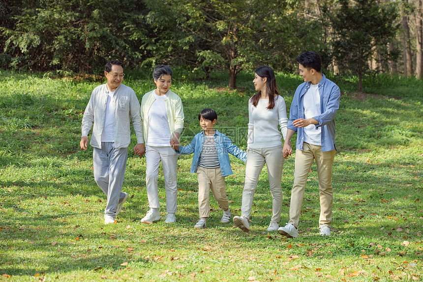 欢乐一家五口手牵手公园草坪散步