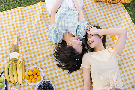 朋友陪伴躺在野餐布上的亲密朋友背景