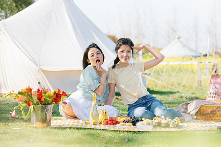 亲密关系野营坐在野餐布上玩闹的闺蜜背景