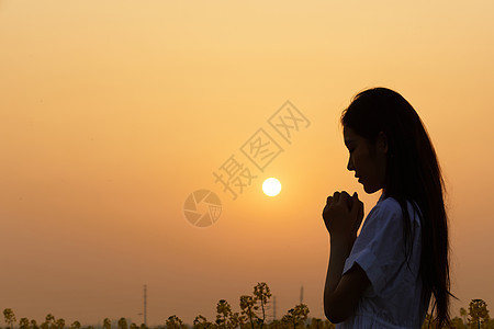 夕阳下祈祷的女性剪影背景图片