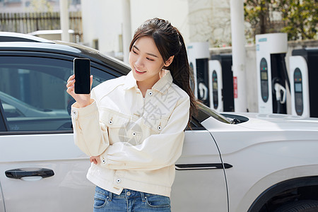 女性站在新能源汽车旁拿着手机高清图片
