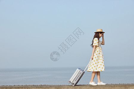 海边游玩,拉着行李箱的年轻女性背景