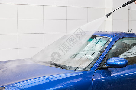 清洁工人拿高压水枪冲洗汽车背景图片