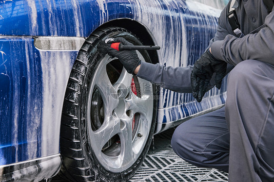 清洁工人清洗汽车刷车洗车轮胎特写图片