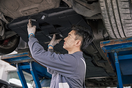 男性汽车修理工检查汽车底盘背景图片