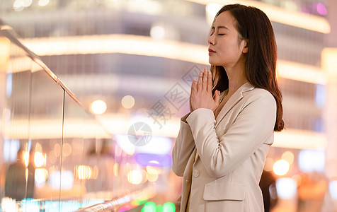 城市里双手合十祈祷的女性图片