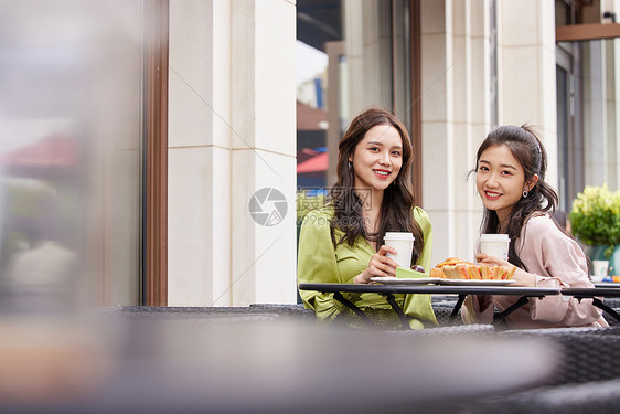 年轻闺蜜们在室外餐桌前一起喝饮料聊天图片