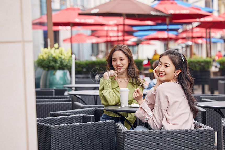 年轻闺蜜们在室外餐桌前一起喝饮料聊天图片