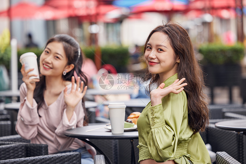 年轻闺蜜们在室外餐桌前一起喝饮料聊天图片