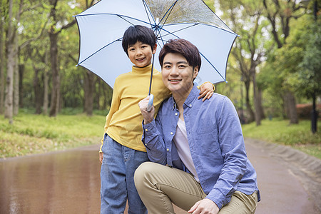 父子下雨天公园里撑伞图片