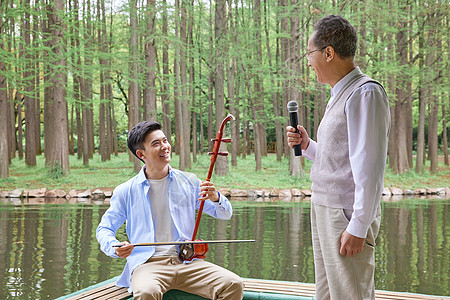 中年父子公园湖边拉二胡唱歌图片素材