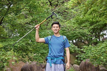 青年男性拿登山杖徒步背景图片