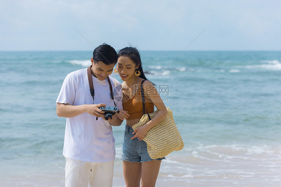 夏日情侣海边沙滩上看相机照片图片