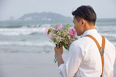 海边西装男性拿着手捧花看海图片