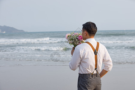 海边男性拿着手捧花看海图片
