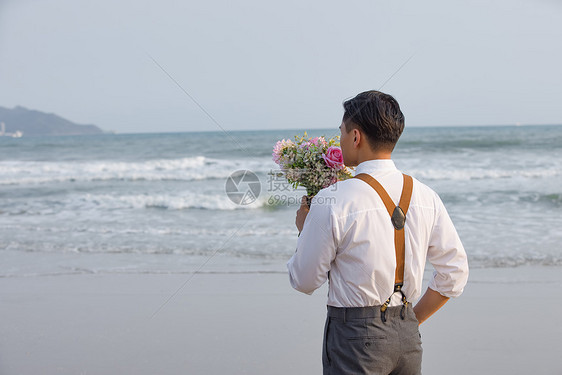 海边男性拿着手捧花看海图片