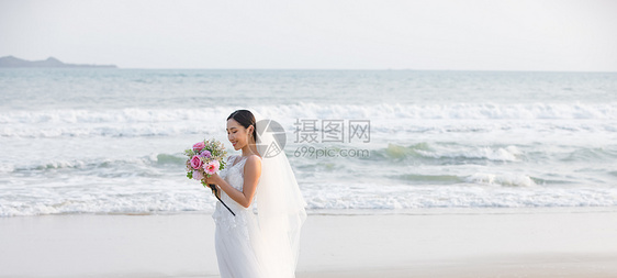 海边婚纱美女拿手捧花图片