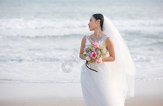 海边婚纱美女拿手捧花图片