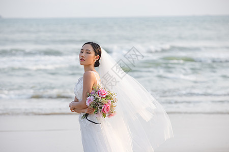 海边婚纱美女拿手捧花图片