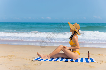 海滩上的人戴草帽比基尼美女沙滩上涂抹防晒背景