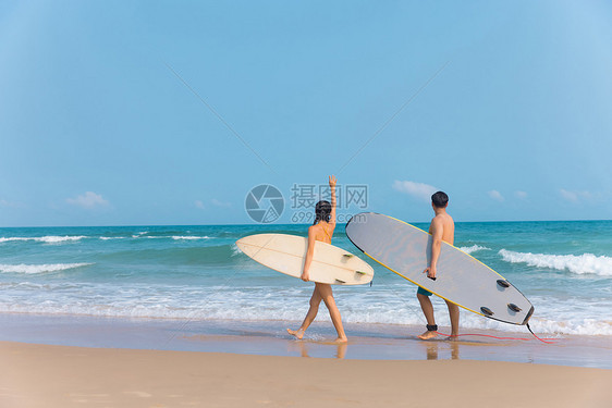 情侣拿着冲浪板海边沙滩上行走图片
