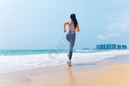 夏日海边沙滩女性运动跑步背影图片