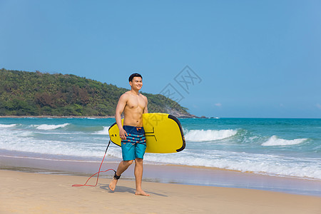 海边沙滩裤青年男性拿冲浪板图片