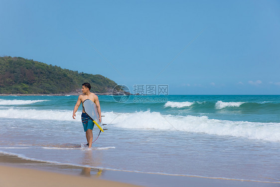 海边沙滩裤青年男性拿冲浪板图片