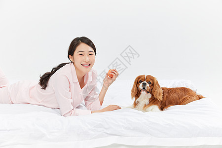 爱宠美女与宠物狗在床上玩球图片