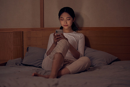 床上追剧的女孩青年女性深夜睡前躺床上玩手机背景