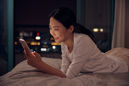青年女性深夜睡前躺床上玩手机图片