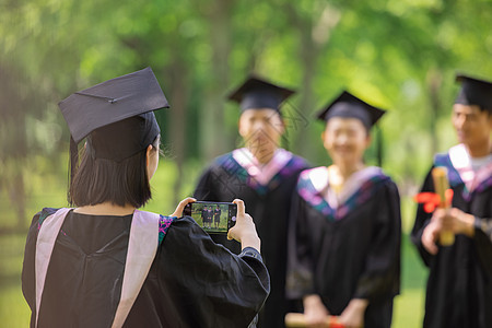 女生用手机给同学们拍毕业照背景图片