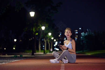 夜晚在公园健身的人坐在跑道上休息图片