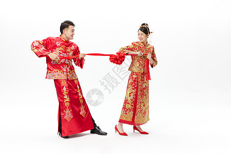 穿中式古装结婚礼服的俏皮新婚夫妻图片