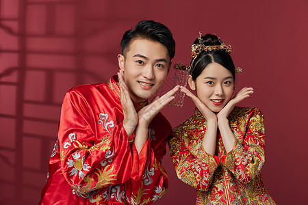 中式婚庆穿中式古装结婚礼服的俏皮新婚夫妻背景