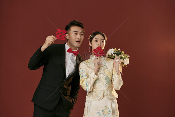 年轻情侣拿着喜字拍中式婚纱照图片