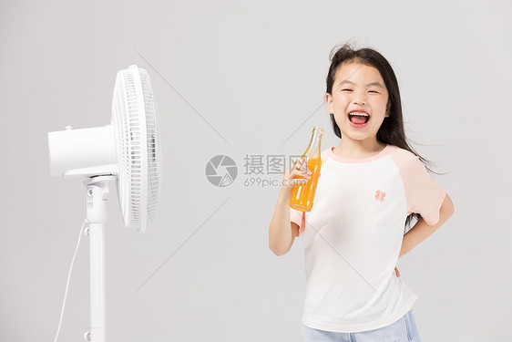 吹电风扇乘凉喝饮料的小女孩图片