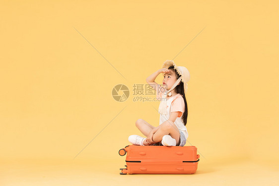 坐在行李箱上眺望远方的小女孩图片