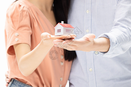 购房证明购房买房的青年情侣手捧房屋模型背景