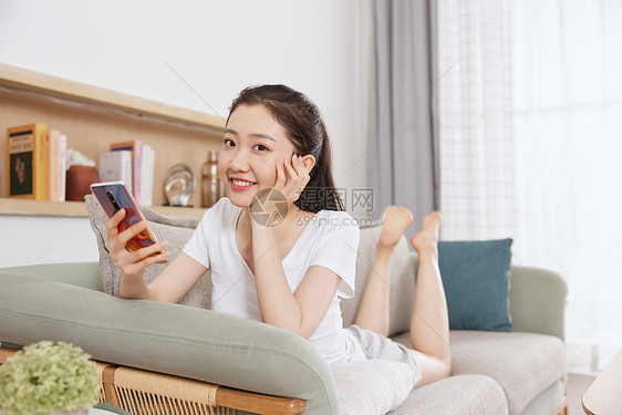 夏日美女趴在沙发上玩手机图片