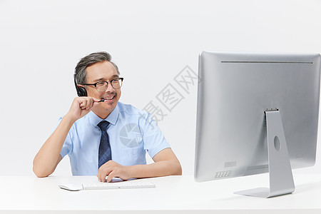 中年男客服在电脑上前打电话图片