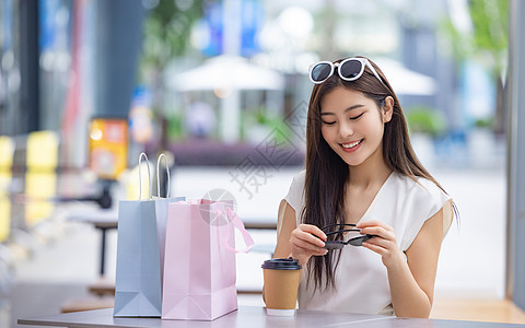 美女购物消费坐在室外咖啡厅背景图片