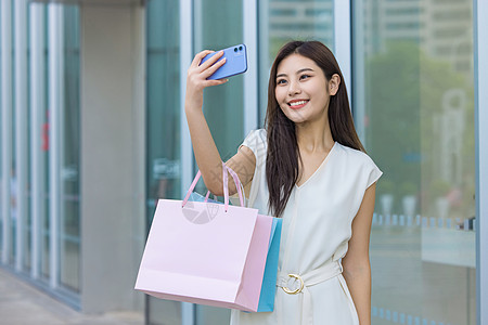 38女王节青年女性逛街拎购物袋手机自拍背景